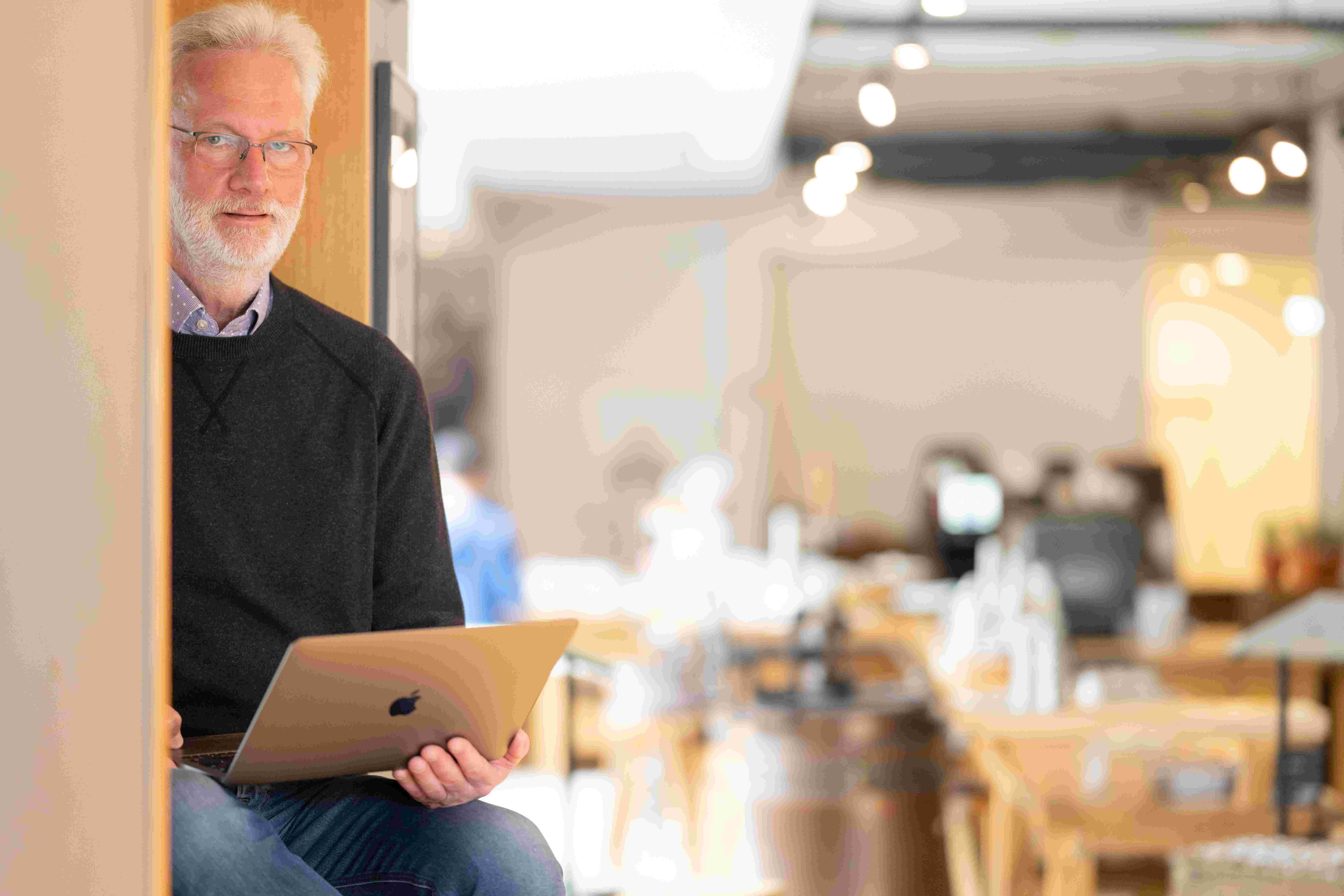 Das Bild zeigt Jürgen Nochhäuser, Inhaber der Agentur für Webdesign, mit einem Laptop und lächelnd in die Kamera schauen.ra 